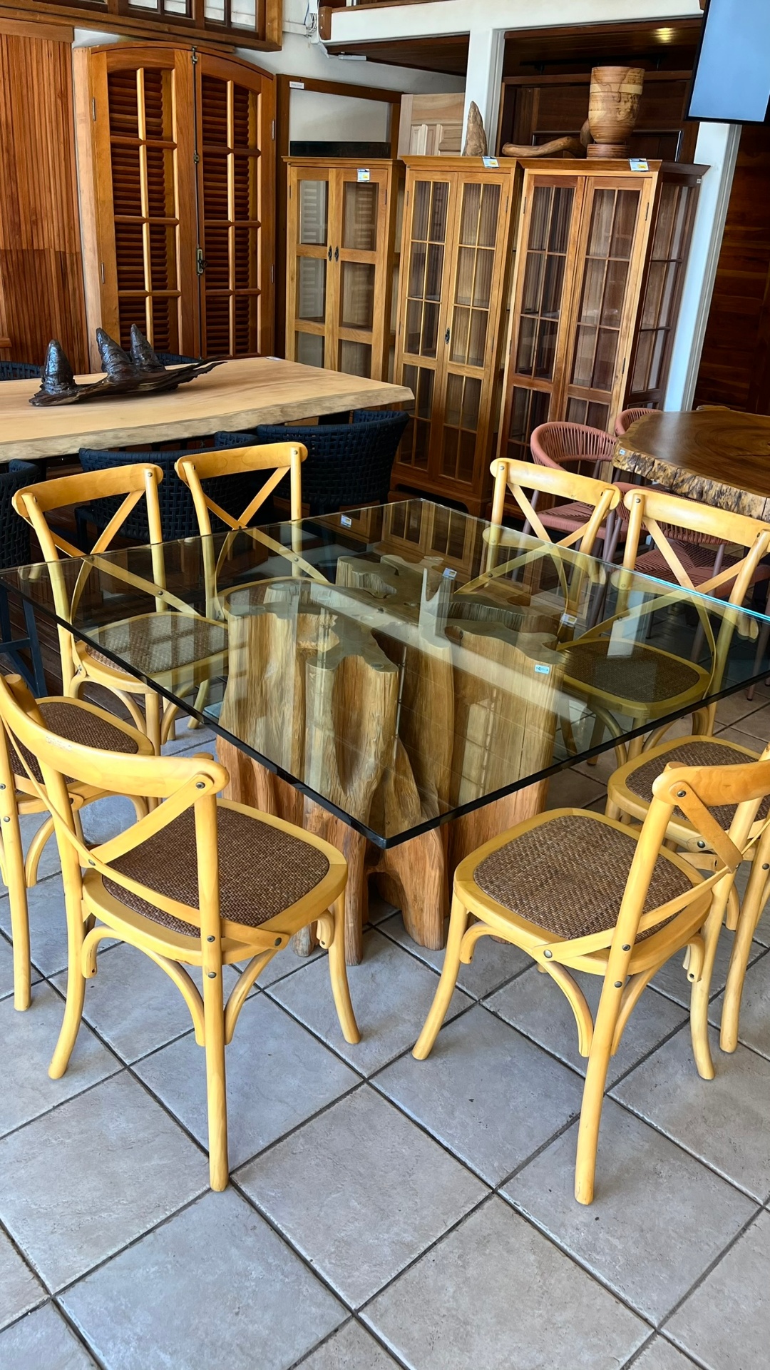 Mesa de jantar com tampo de vidro sobre base em troncos
